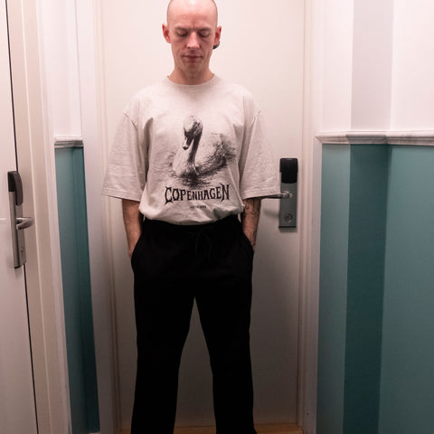 Person wearing a white t-shirt with 'Copenhagen' graphic design in a room.